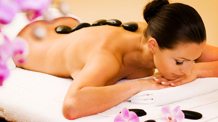 Massage du corps avec des pierres chaudes énergisantes. 